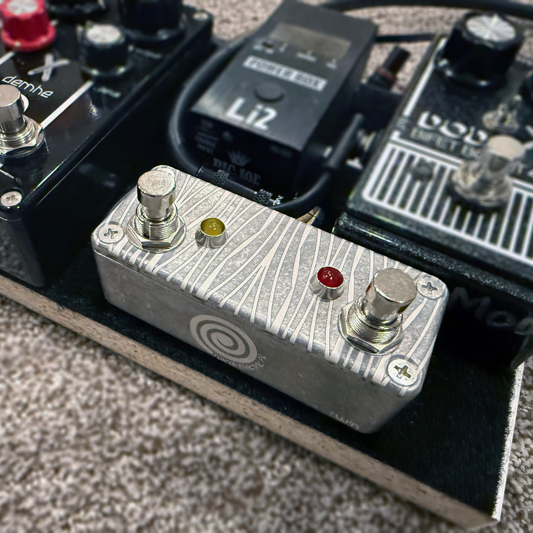 Mini latching channel/FX switcher with laser-etched art deco frond pattern.